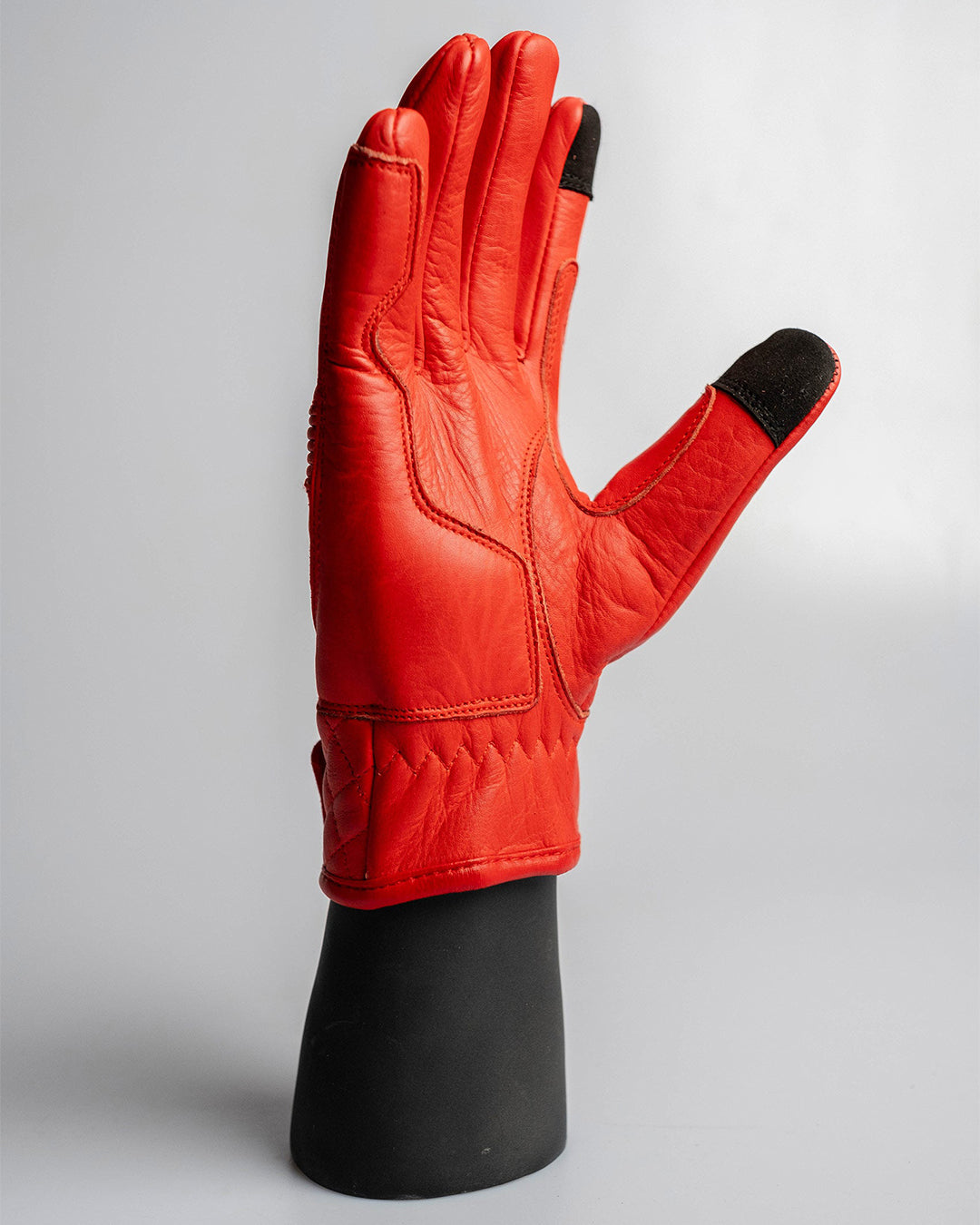 Palm side of red Merla Moto motorcycle gloves featuring padded palms and perforated fingers for grip and ventilation