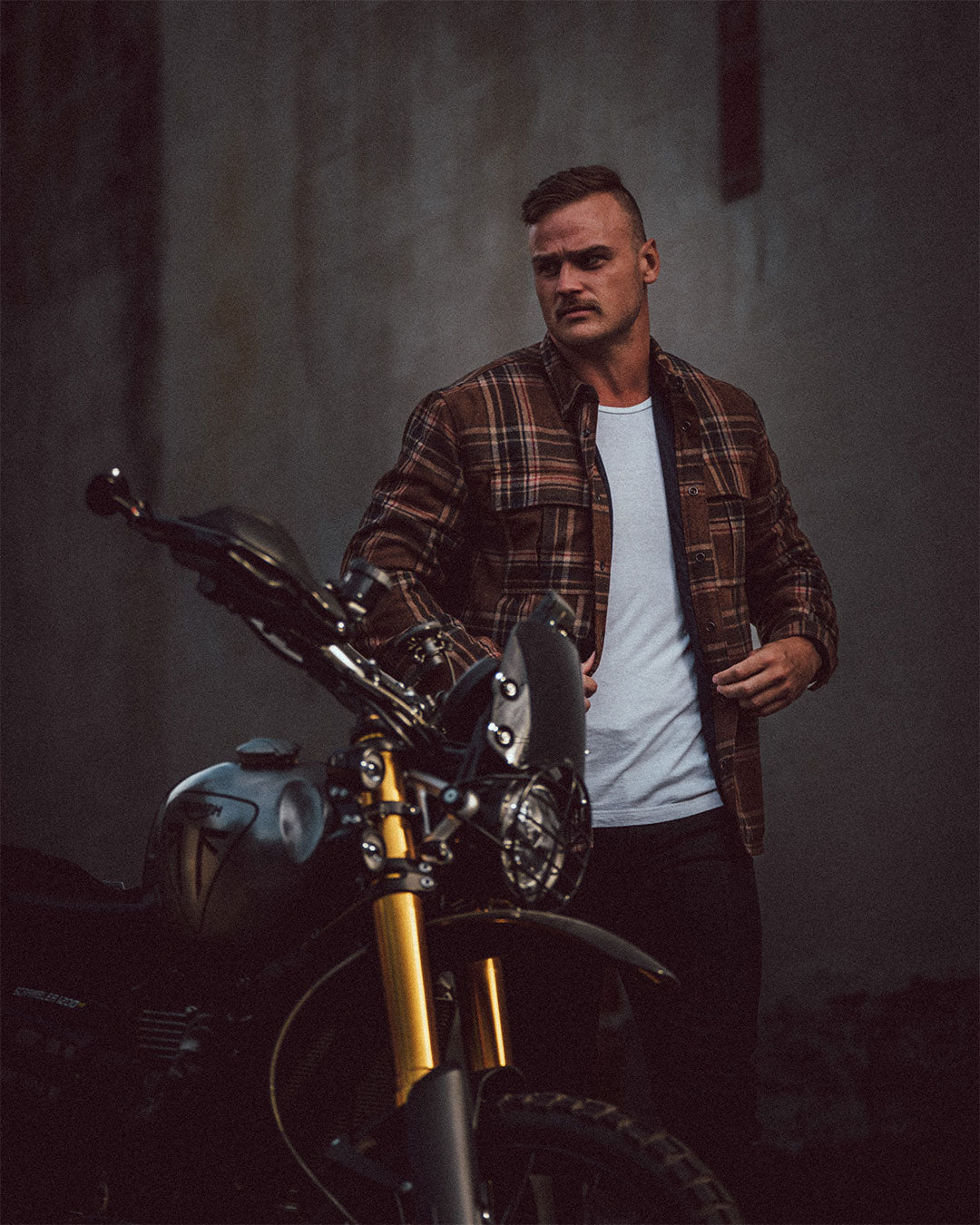 Motorcyclist next to bike wearing Denver shacket with wool exterior and DuPont™ Kevlar® fiber liner, designed for thermal insulation and abrasion protection