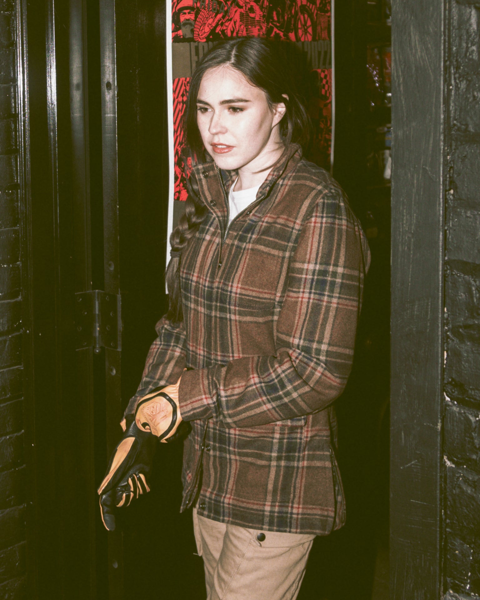 Stylish woman in brown plaid flannel, Kevlar-lined shacket with armor pockets for shoulder, elbow, and back protection, designed for riding and casual use