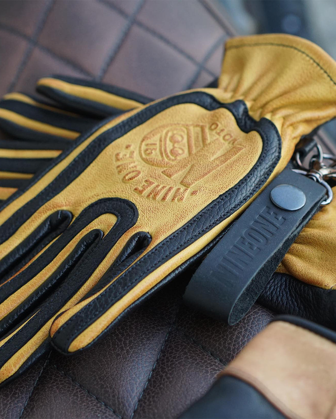Close-up of yellow and black motorcycle gloves made from 100% genuine deerskin, featuring ergonomic design and premium stitching for durability.