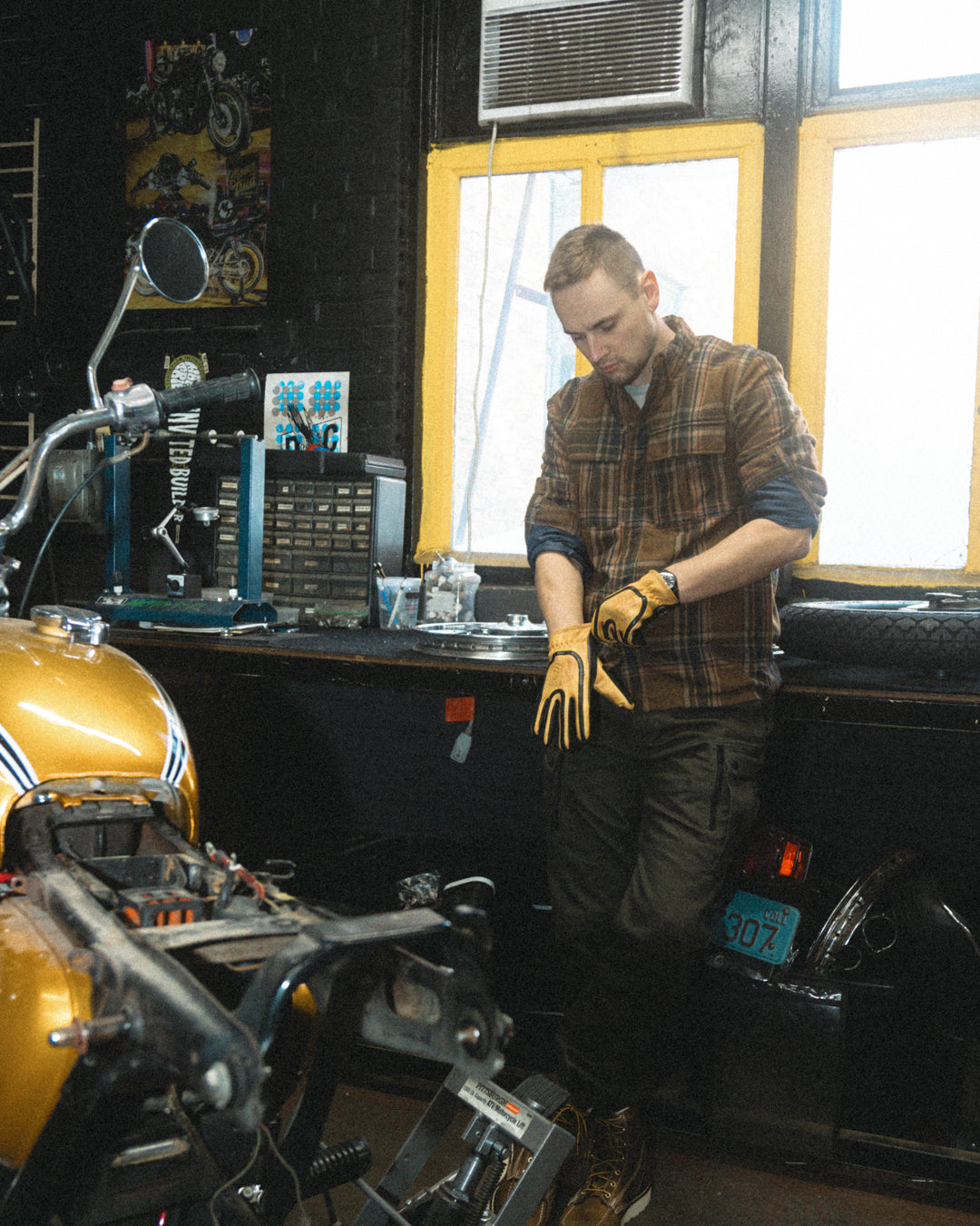 Man putting on touchscreen-compatible yellow and black deerskin motorcycle gloves, designed with ergonomic fit and reinforced stitching
