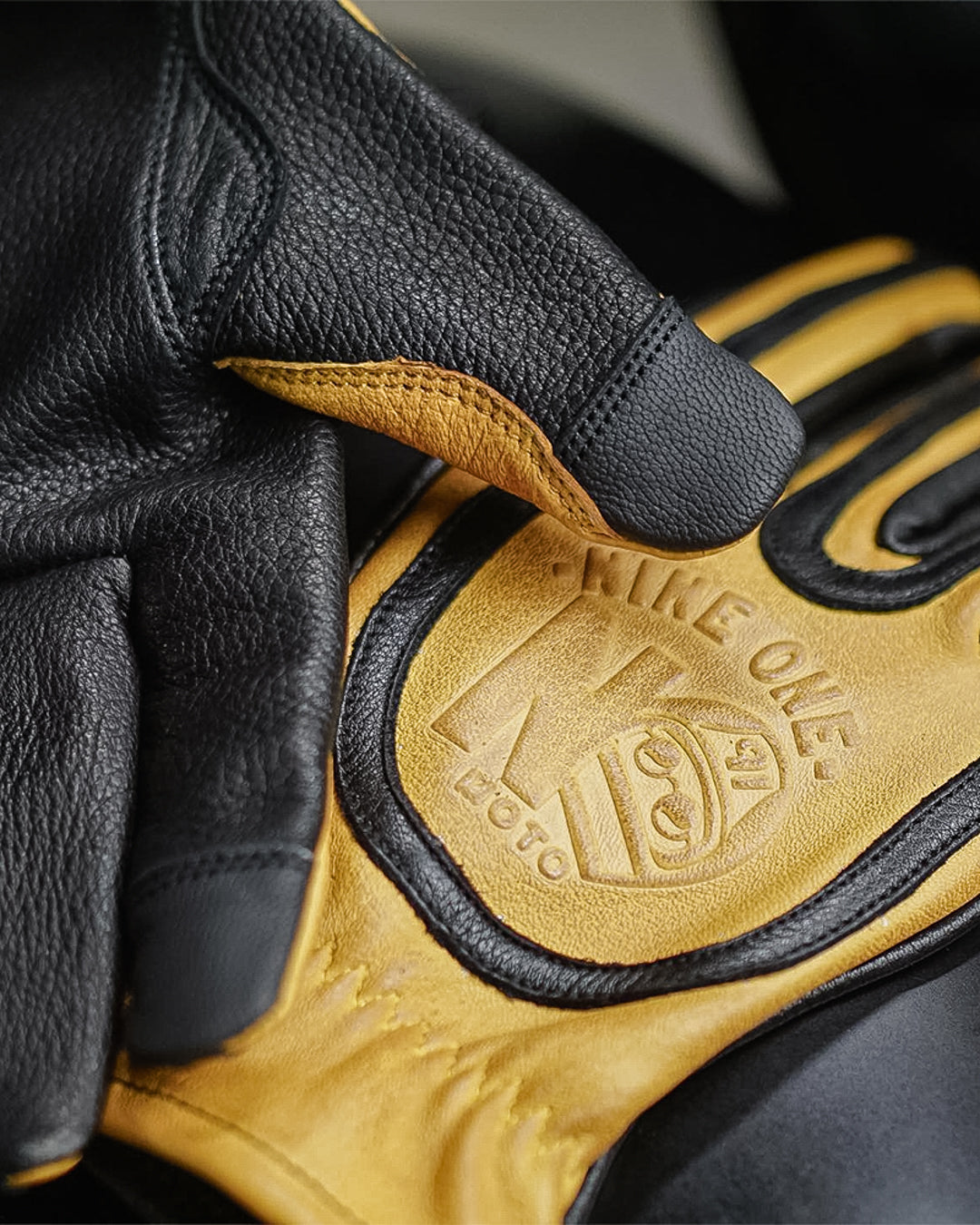 Closeup of yellow and black deerskin touchscreen motorcycle gloves, designed for comfort and precision, with premium stitching for durability.